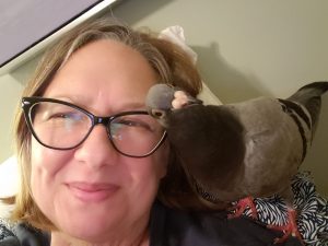 Smiling woman with happy rescued pigeon on her shoulder